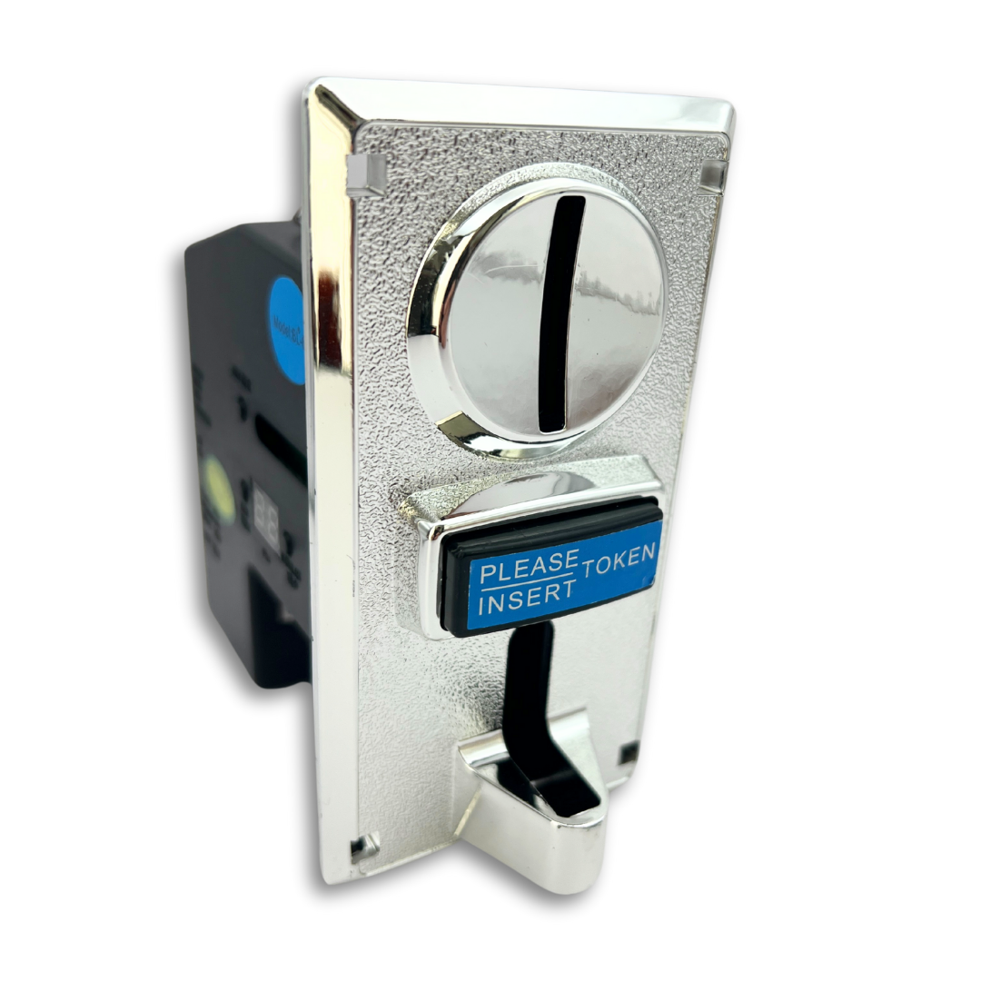 Front angled view of arcade coin acceptor with chrome faceplate and blue "PLEASE INSERT TOKEN" label on the push flap