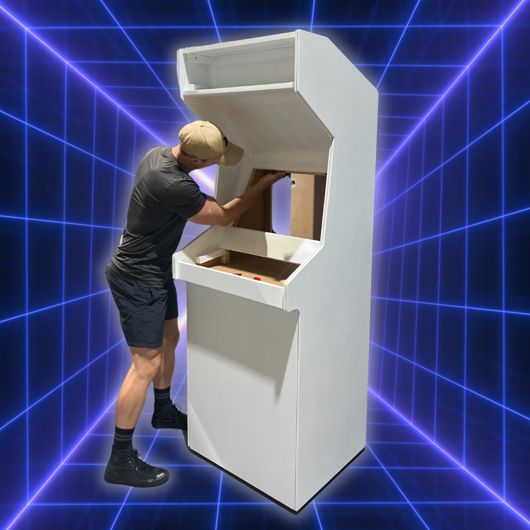 Person assembling a white painted undercoat DIY arcade machine during the building and customization phase, showing structural progress from the Arcade Revival step-by-step guide.