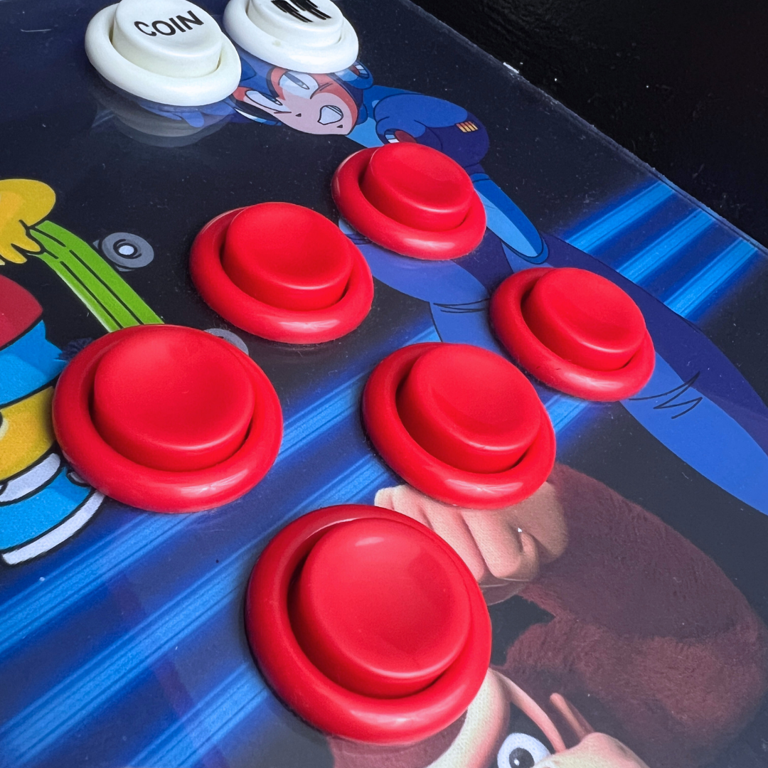 Close-up of red arcade buttons with white coin buttons installed on a retro arcade machine control panel.