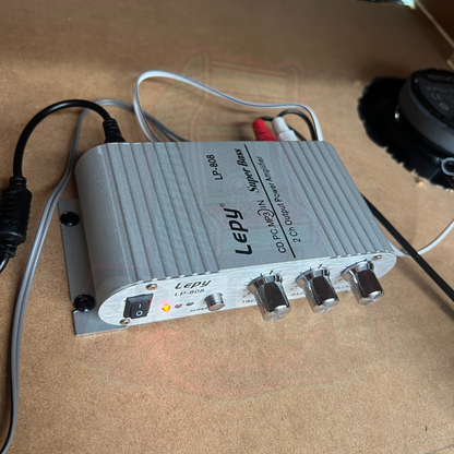 Amplifier installed inside an arcade machine with wiring connected to speakers and power supply for sound output.