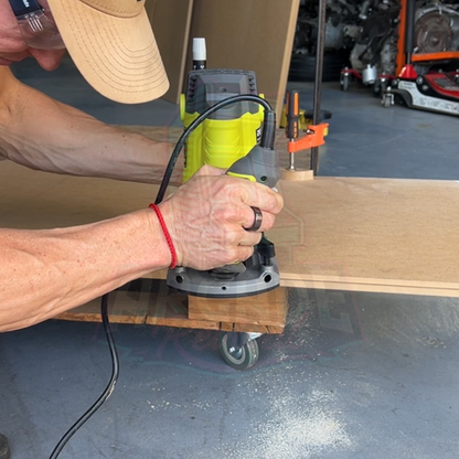Person using a router to cut MDF arcade cabinet side panel during arcade machine build, part of the Arcade Revival DIY guide.