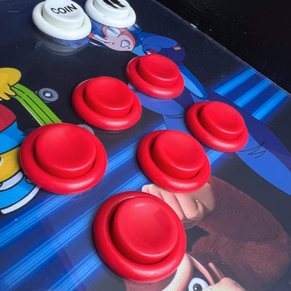 Close-up of red arcade buttons with white coin buttons installed on a retro arcade machine control panel.